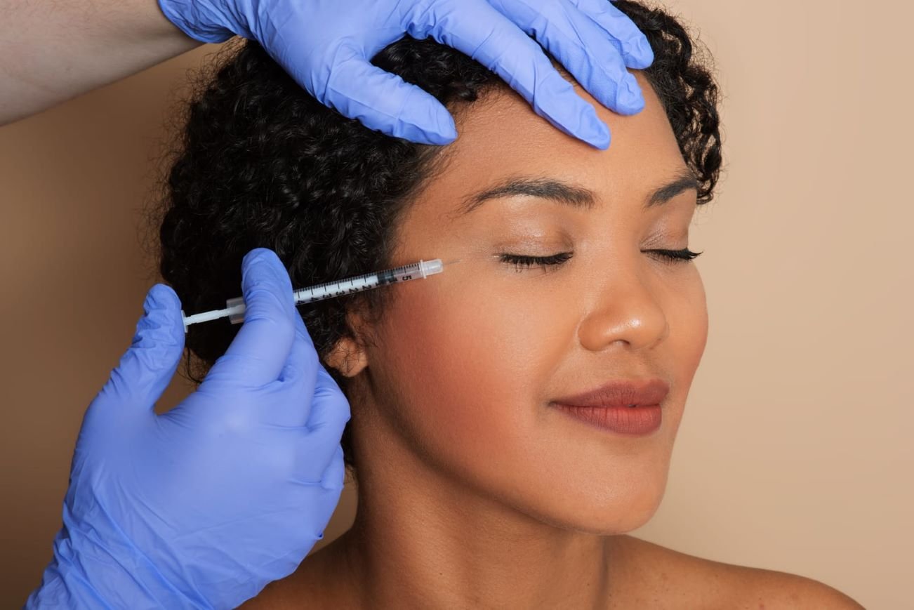 Aesthetic professional administering a Sculptra injection to a woman’s face, targeting skin rejuvenation and collagen production.