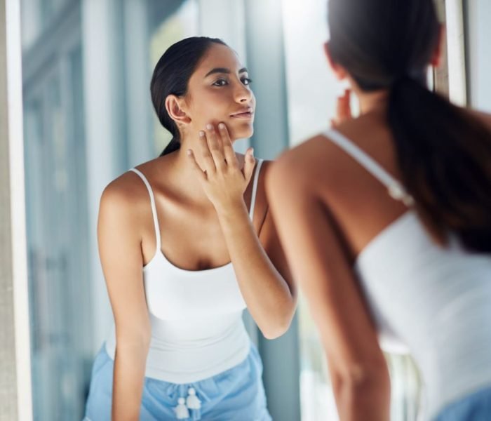 Woman examining her skin in the mirror after Morpheus8 treatment for facial rejuvenation